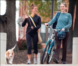 Two female students walking with bike and dog