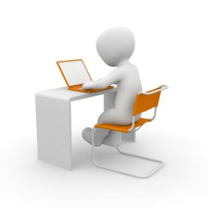 White, featureless cartoon figure at desk typing on an orange laptop.