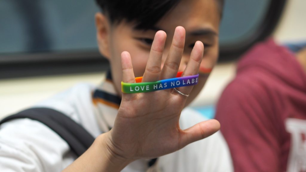 person holding up a rainbow bracelet