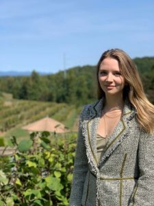 Bethany Rand poses in front of a vineyard